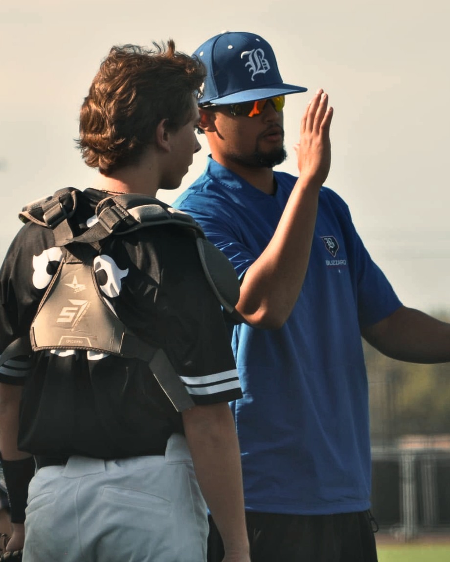 Bryan Sanchez coaching a catcher on the field.